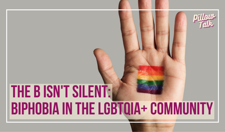 Open hand with a rainbow flag painted on the palm. The hand is on a gray background.. A white frame surrounds image, text in magenta "The B Isn't Silent: Biphobia In The LGBTQIA+ Community". "Pillow Talk" in magenta cursive is in upper right corner.