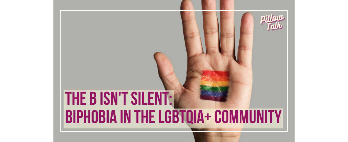 Open hand with a rainbow flag painted on the palm. The hand is on a gray background.. A white frame surrounds image, text in magenta "The B Isn't Silent: Biphobia In The LGBTQIA+ Community". "Pillow Talk" in magenta cursive is in upper right corner.