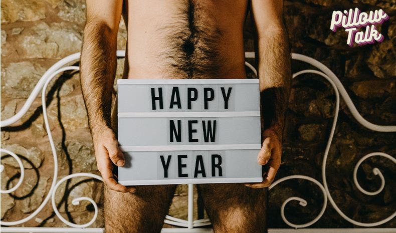 torso of a naked man holding a light up sign board in front of his groin that says "happy new year"