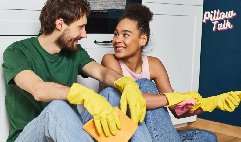 a man and a woman sitting together on the floor looking at each other with yellow rubber gloves on