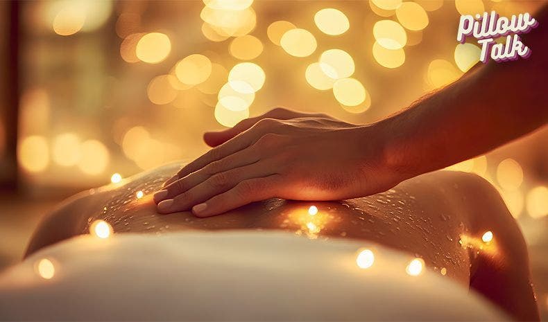 Hands on someone's back giving a sensual massage in candle light