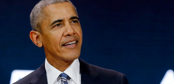 President Barack Obama wearing a blue suite, white shirt, and blue striped tie, standing, looking to the left