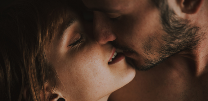 White couple intimately kissing. Woman (LEFT) has mouth slightly open and eyes closed. Man (RIGHT) is kissing her lips, eyes closed, and patched beard.